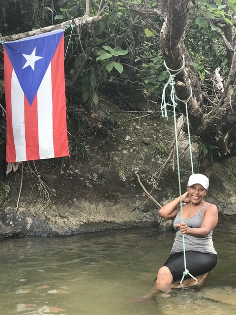 Woman sitting on a swing next to a Puerto Rican flag.