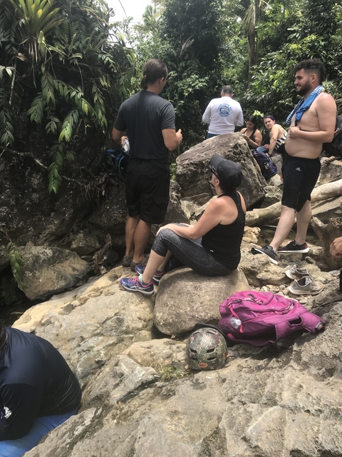 Group of people resting on rocks by a creek.