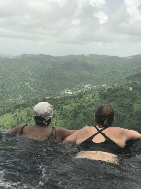 Two women enjoying a view from the edge of a pool.