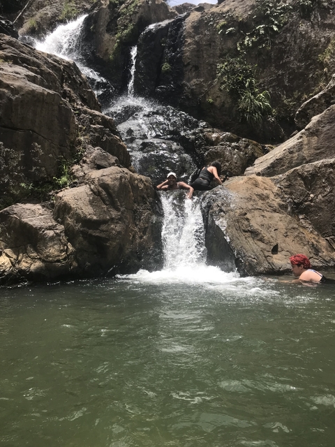 Two people enjoying a rock pool and waterfall.