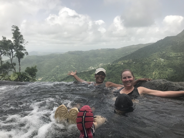 Two women in a rock pool with a scenic view.