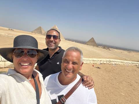 Three people with pyramids in the background.