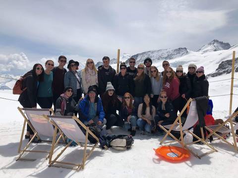 Group of people on a snowy mountain with a clear sky.