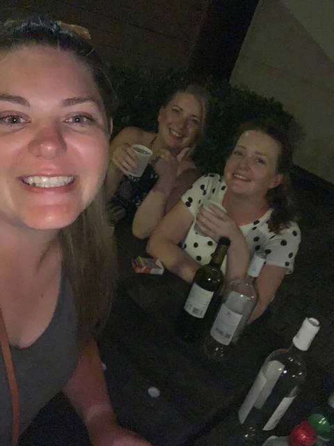 People sitting at a table with drinks in a dim room.