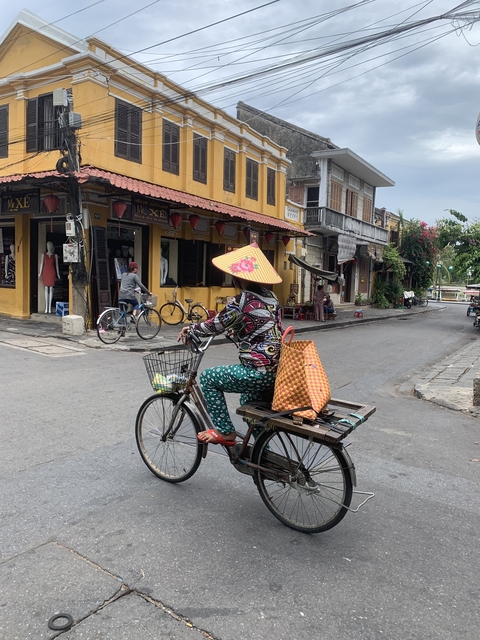 Person in colorful clothing riding a bicycle in a traditional street.