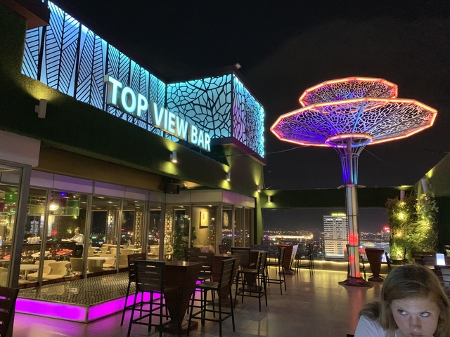 Rooftop bar with neon lights and city view at night.