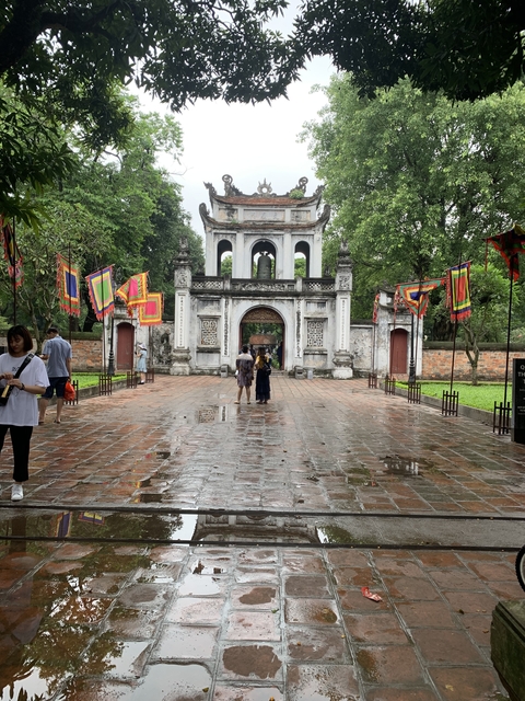 Temple entrance with decorative flags on a rainy day.