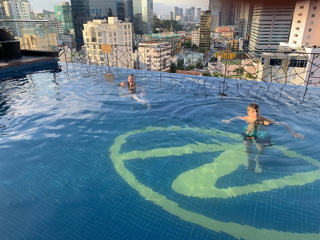 People swimming in a rooftop pool with city views.