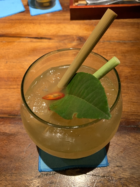 Close-up of a cocktail with a chili and leaf garnish.