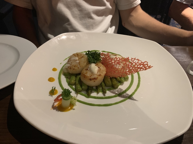 Plated dish featuring scallops and asparagus beautifully arranged.