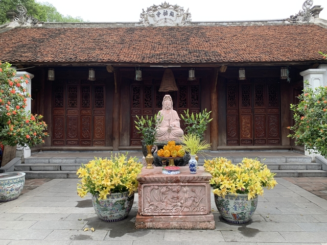 Statue with floral offerings at a traditional temple.