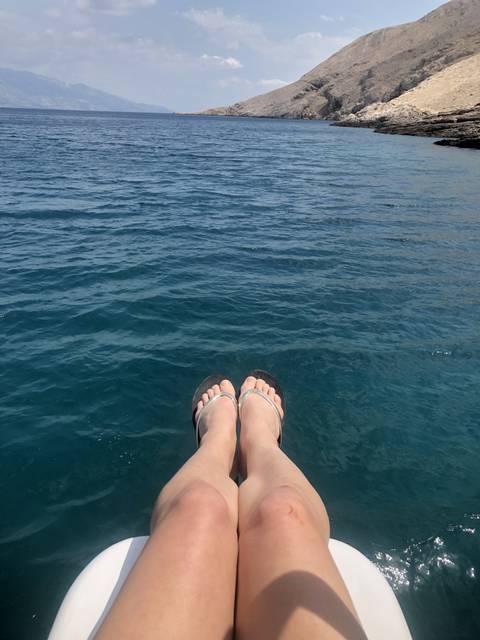 Feet in sandals over a view of the sea.