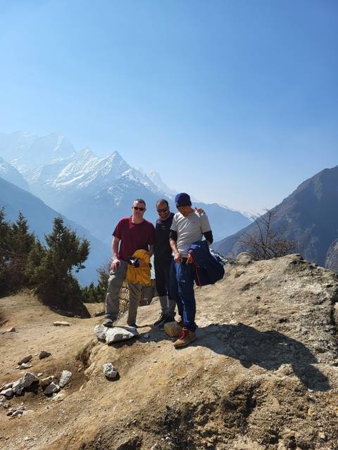 Three people posing on a rocky mountain trail.