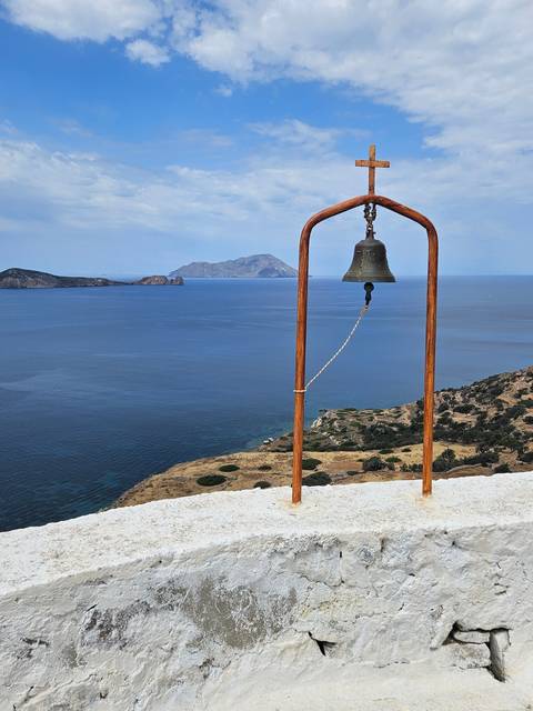 A bell with ocean view in the background.