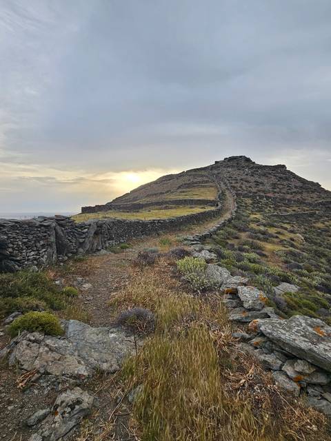 Hiking trail with stone walls and a cloudy sky.