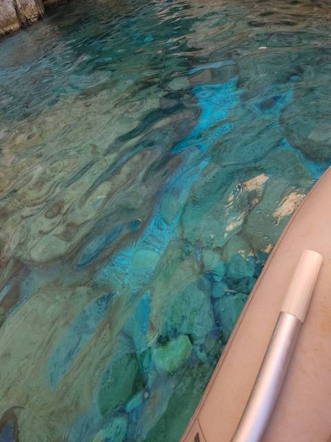Close-up view of clear water with rocks underneath a boat.