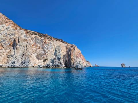 Coastal cliffs meeting the deep blue sea under a clear sky.