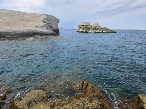Rocky seaside with blue water and a small island formation.