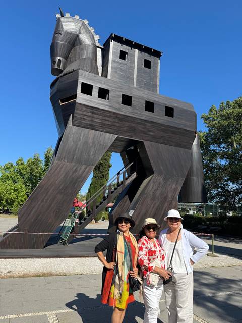 Group posing in front of a wooden horse structure.