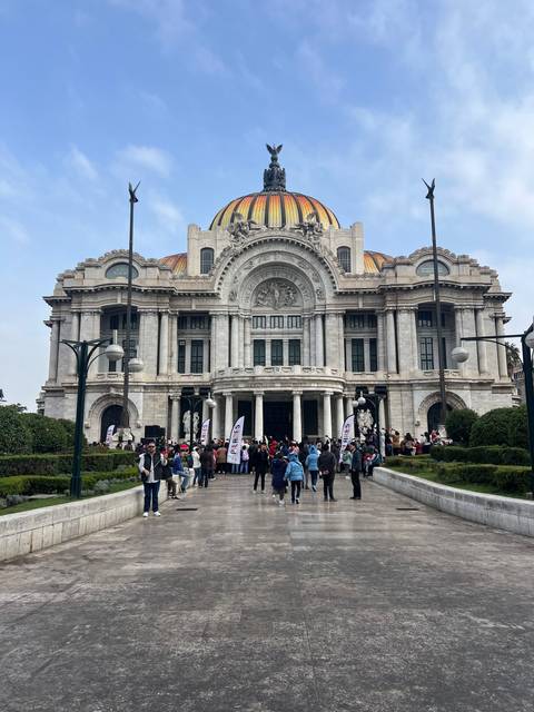 Exterior of a grand historic building with a group of people in front.