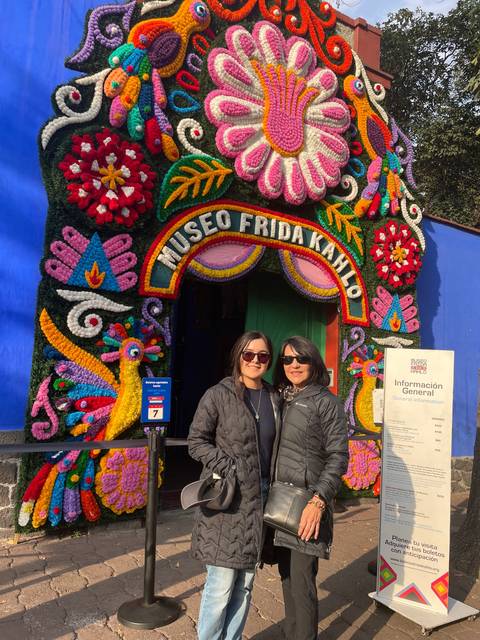 Two people posing in front of a colorful museum entrance.