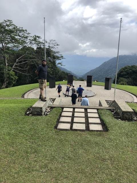 People visiting a memorial site on a hillside.