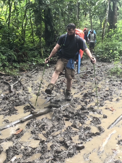 Person walking through a muddy forest path.