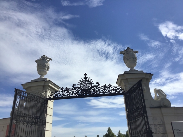 Wrought iron gate of a historic palace with blue sky.