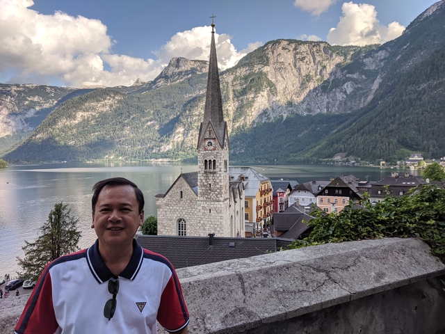 Man with scenic view of a church and lake in the background.