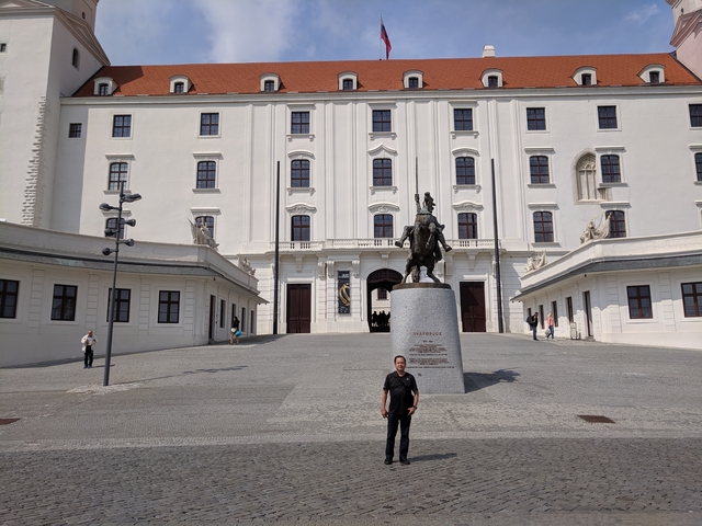 Man standing in front of a historical building with a statue.