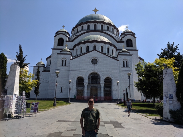 Man in front of a large church with domes.
