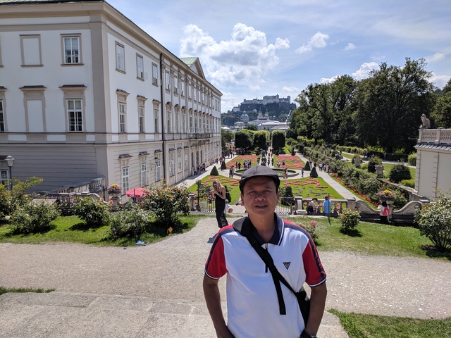 Man in a garden with a castle in the background.