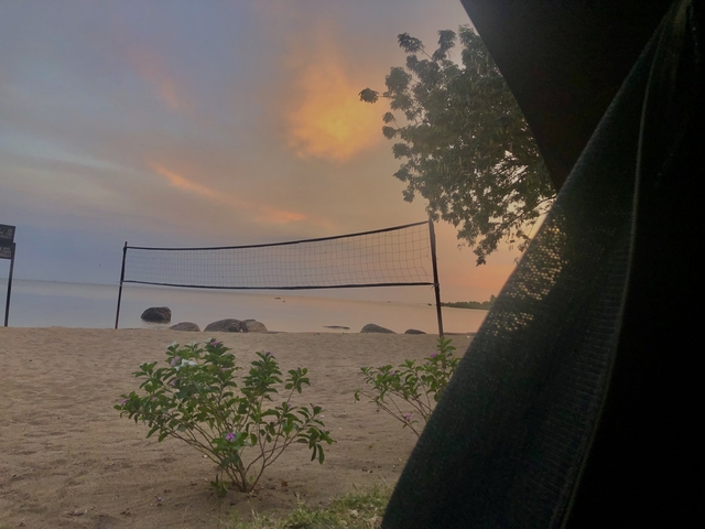 A sunset view on a beach with a volleyball net.