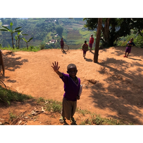 Children playing and waving on a dirt path.