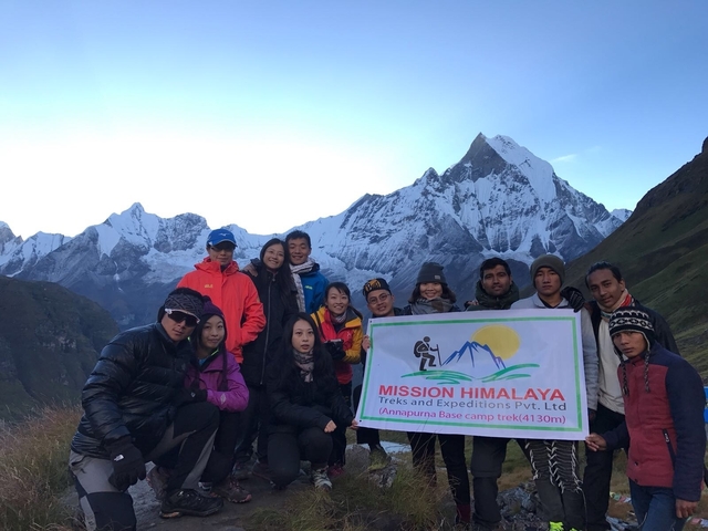 A group of people with a banner saying Annapurna Base Camp trek.