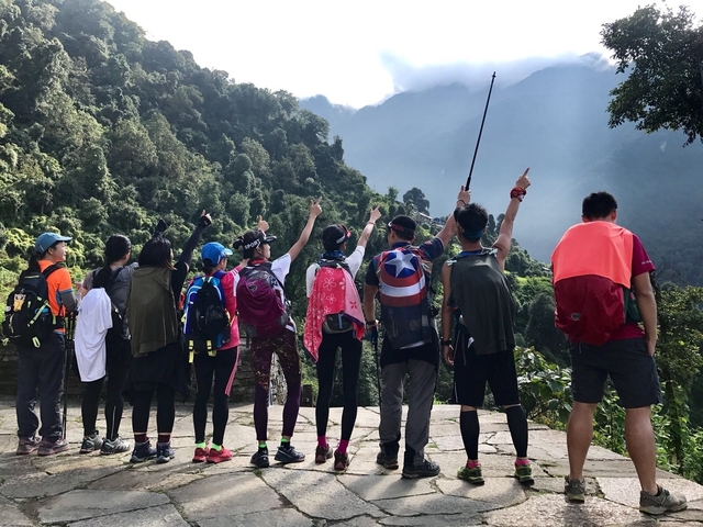 A group of hikers pointing towards the mountain view.