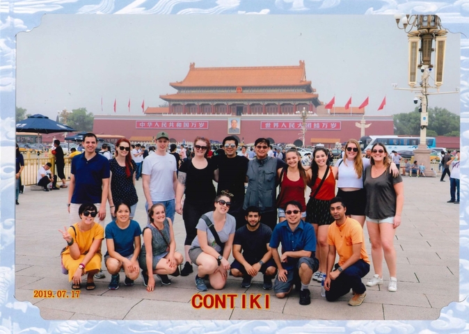 A group of tourists posing in front of Tiananmen Square.
