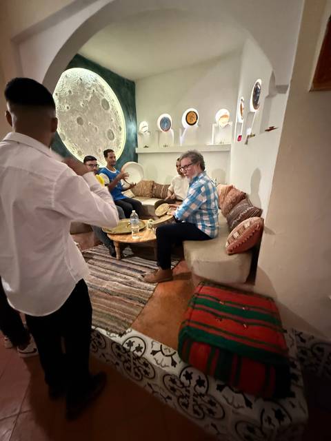 People relaxing in a room with traditional decor and carpets.