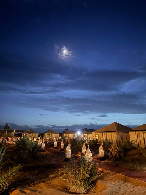 Night scene of a camp with ornamental tents and lighting.