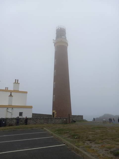 Lighthouse standing tall in a foggy atmosphere.