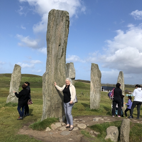 A group of people around standing stones in a grassy area.