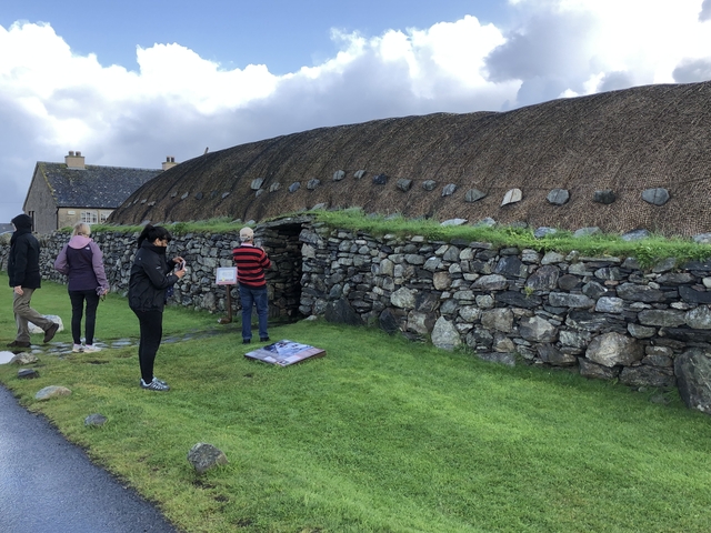 Tourists exploring a traditional thatched stone house