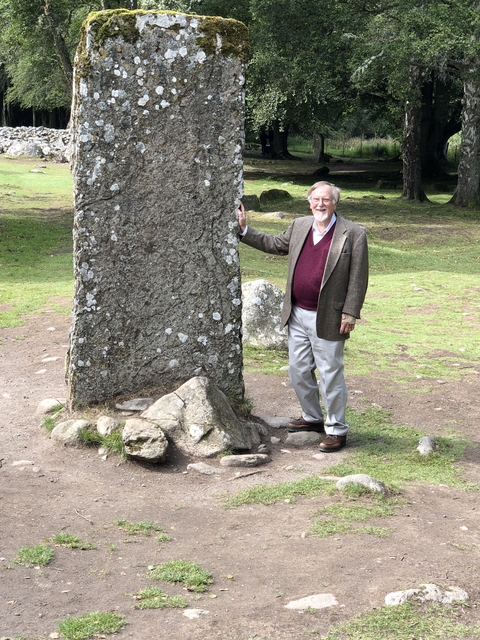 Man standing next to a tall stone in Callanish
