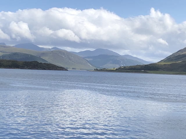 Large body of water with mountainous backdrop under a partly cloudy sky