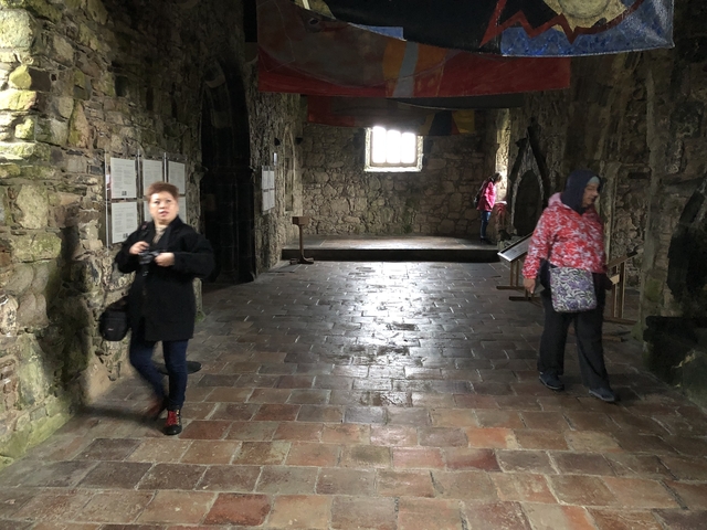 Interior of a historic stone building with visitors.