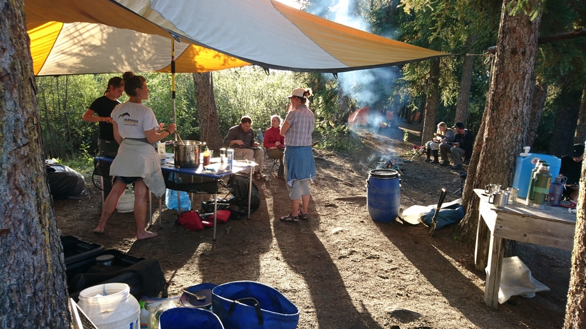 Outdoor campsite with people under a tent.
