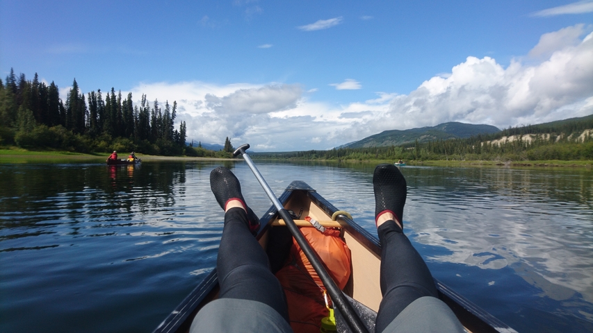 Person canoeing on the river looking at the skies.