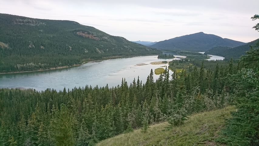 Wide view of a river landscape surrounded by mountains.