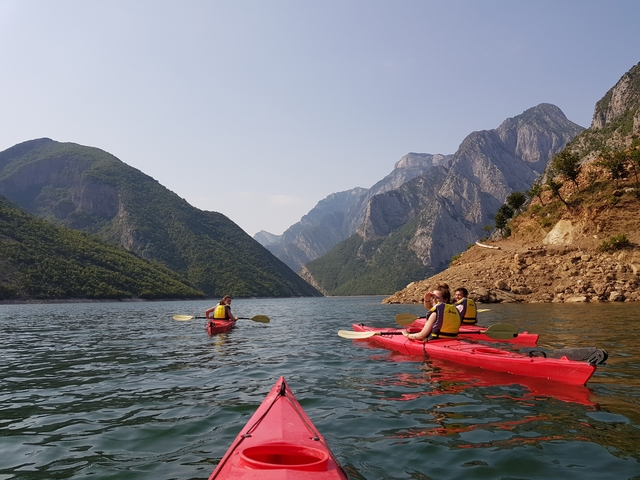 Kayakers in red kayaks exploring a scenic mountain lake.