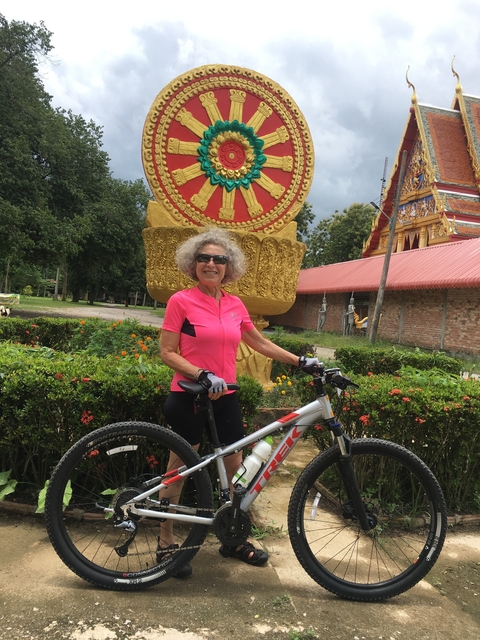 Cyclist smiling in front of a large golden sculpture.
